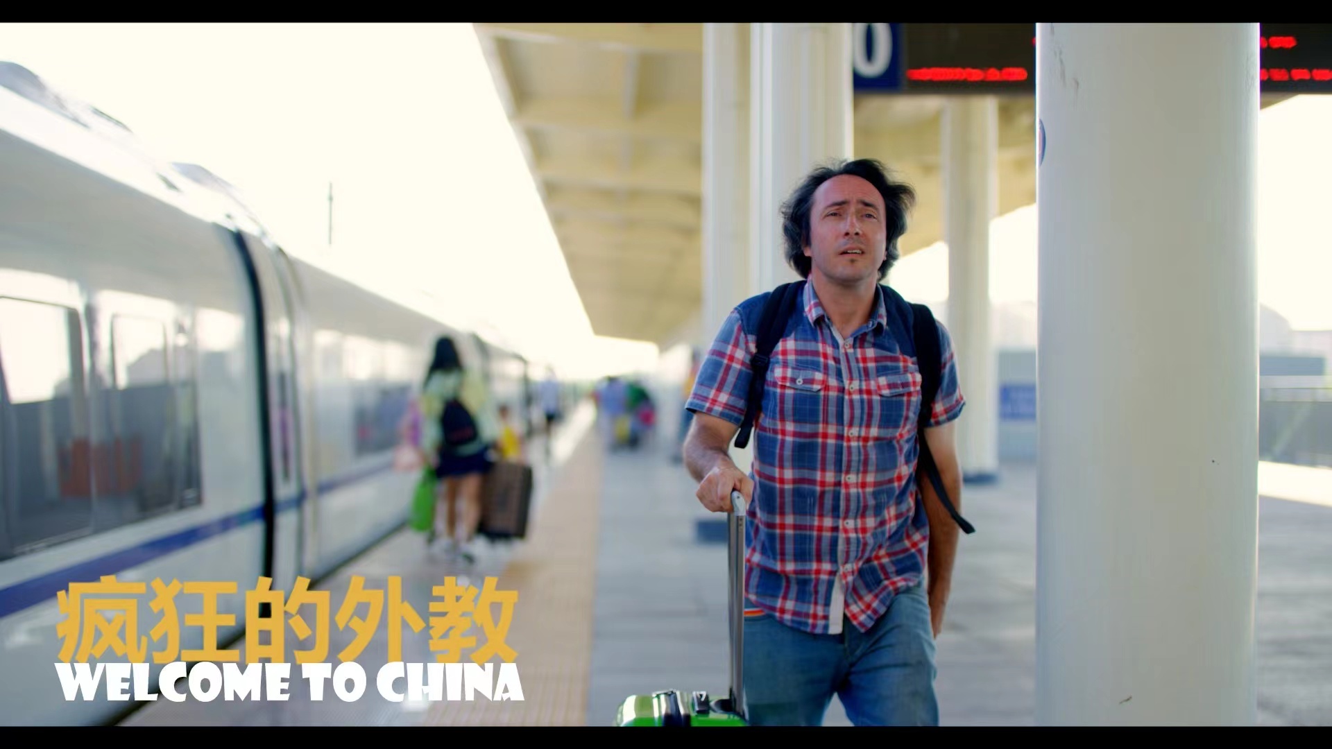 主人公带着行李箱站在中国一座火车站的站台上。